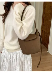 Brown lychee leather pumpkin bucket bag shown on model in a cozy home setting
