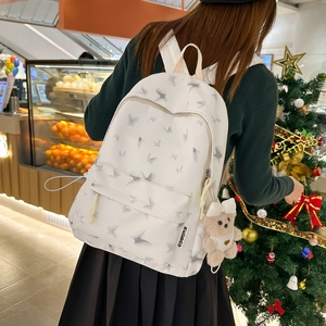 Détail du sac à dos en nylon blanc avec imprimé papillon et pendentif ours