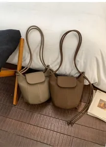 Detailed view of bucket bags in pebble leather featuring refined textures and shoulder straps