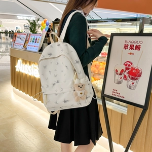Détail du sac à dos d'école en nylon blanc avec imprimé papillon et breloque ours brun