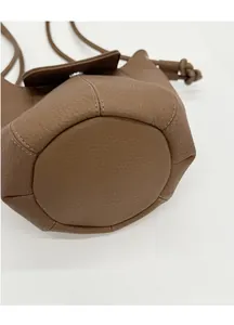 Detail of reinforced circular base with brown lychee texture leather on bucket bag