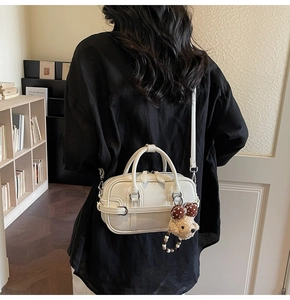 Detail of cream white mini crossbody bag with cute dog charm and polka dot bow