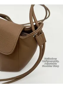 Detail of earthy brown lychee texture leather bucket bag with adjustable shoulder strap