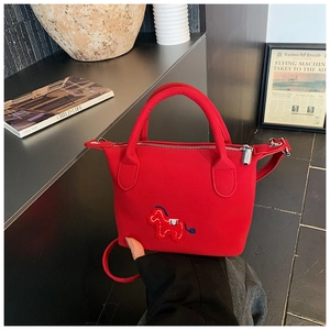Détail du sac seau en nylon rouge avec broderie de cheval et poignées cylindriques