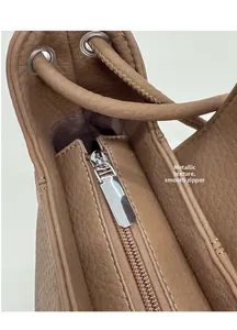 Close-up of brown litchi grain leather bag featuring silver metal zipper and drawstring