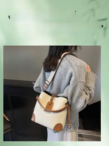 Detail of color-block bucket bag showing beige lychee texture and brown strap details