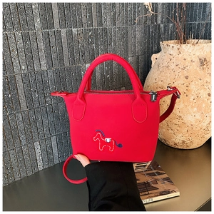 Détail du sac seau rouge avec broderie de cheval bleu et poignées de transport