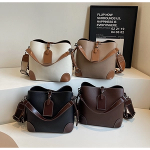 Detail of four vintage bucket bags in various colors on a white display with wide straps