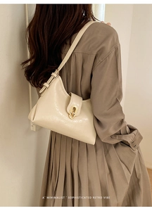 Detail of a creamy white retro leather crescent bag with a gold oval metal buckle