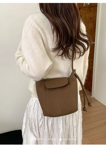 Detail of dark brown leather pumpkin bucket bag with vertical stitching and drawstring