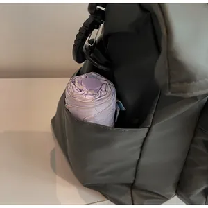 Detail of dark green tote side pocket holding a purple umbrella for storage capacity