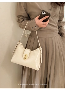 Detail of a creamy white retro leather tote featuring a gold oval twist lock and adjustable strap