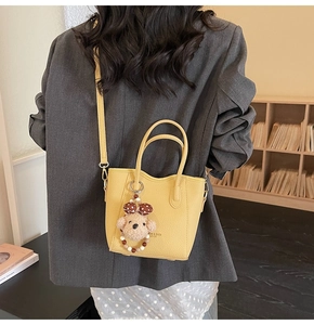 Detailed back view of a yellow leather bucket bag with teddy charm and shoulder strap