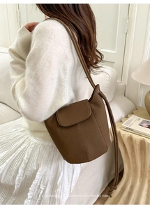 Detail of vintage brown pebble leather bucket bag shown on a model in a cozy indoor setting