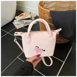 Gros plan détaillé du mini sac seau rose avec broderie de poney en peluche 3D et sangle