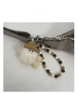 Detail of plush monster bag charm with crochet hat and beaded strap on a handbag