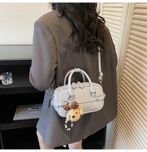 Detail of light grey-blue faux leather handbag with a plush puppy charm and ribbon
