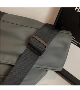 Detail of adjustable wide nylon shoulder strap and matte buckle on dark grey tote bag
