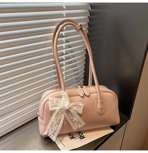 Détail du sac Boston en cuir rose avec nœud en dentelle blanche et fermeture éclair double