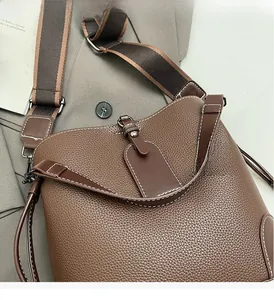 Close-up of brown pebbled leather bucket bag with white contrast stitching and wide strap