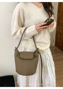Close-up of brown textured leather bucket bag featuring white contrast stitching and minimalist flap
