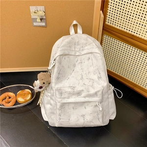 Detail of white marble print backpack with lightning embroidery and plush bear charm