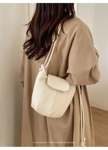Minimalist beige bucket bag detail showing premium pebbled leather and crossbody strap style