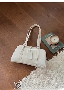 Close-up of cream Boston bag with adjustable straps on a cozy rug with decor