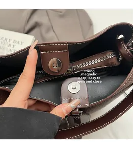 Detail of contrast bucket bag featuring a strong magnetic buckle and inner zipper pocket