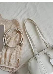 Close-up of white leather shoulder bag with adjustable strap and silver metal hardware