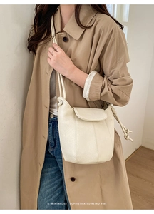 Close-up of minimalist retro bucket bag featuring cream lychee texture and knot shoulder strap