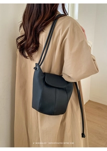 Minimalist black lychee texture leather bucket bag shown on khaki trench coat