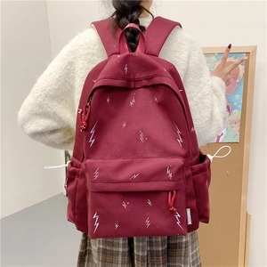 Macro shot of burgundy student backpack featuring white lightning patterns and side pockets