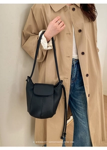 Black lychee texture bucket bag shown with khaki trench coat in minimalist street style