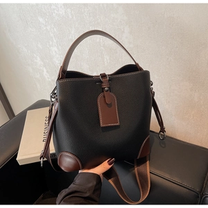 Close-up of contrast-color leather bucket bag with wide strap and pebble texture