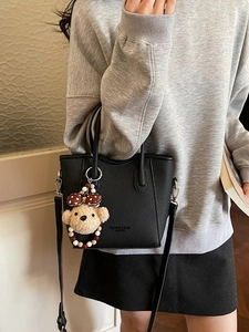 Classic black litchi pattern bucket bag with a cute bear pendant worn by a model