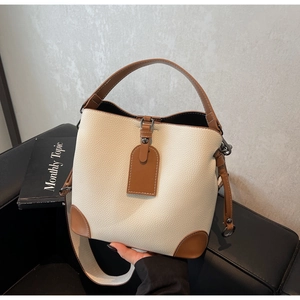 Detail of color-block bucket bag showing cream pebble leather and brown trim highlights