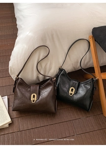 Close-up of vintage black and dark brown underarm bags with glossy pleated leather and gold buckle