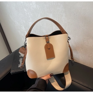 Detail of contrast bucket bag with lychee pattern leather and wide woven shoulder strap
