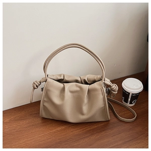 Detail der beigen Plissee-Schultertasche mit Knotendesign und rundem Griffmuster