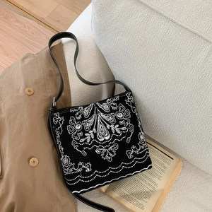 Détail du sac seau en toile noire avec broderie florale ethnique blanche complexe