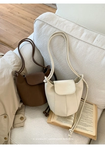 Detailed view of minimalist leather pumpkin bucket bags with fine grain on a soft sofa
