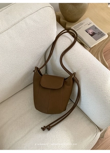 Detailed close-up of retro brown pebbled leather bucket bag on minimalist sofa