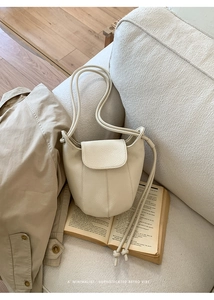 Detailed macro view of cream pumpkin-shaped bag on open book with retro minimalist vibe