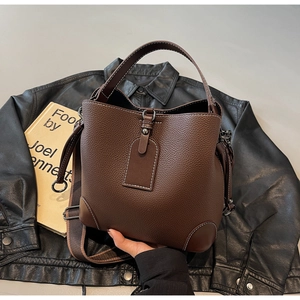 Detail of dark brown pebble leather bucket bag with white contrast stitching and wide strap