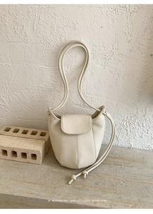 Close-up of beige pumpkin bucket bag with lychee texture and thin shoulder straps