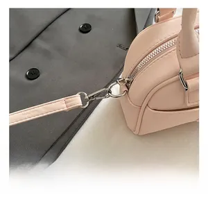 Détail des crochets en métal argenté et du connecteur de bandoulière sur sac en cuir rose