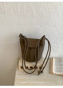 Detailed view of dark brown pebbled leather bucket bag with vertical stitched accents