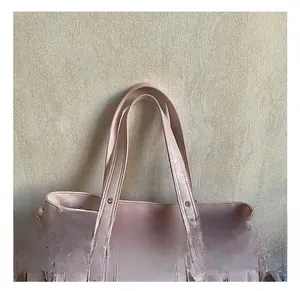 Close-up of pink litchi grain leather tote bag with metal rivets and decorative zippers