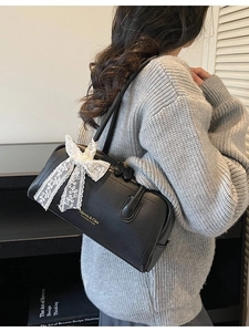 Sac Boston en cuir noir grainé avec nœud en dentelle porté à l'épaule
